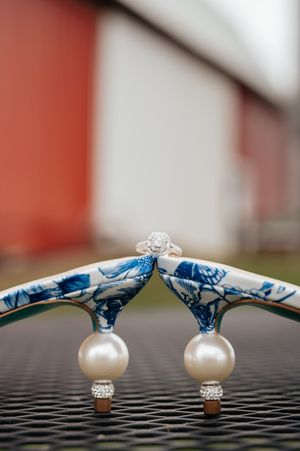 Pearl and crystal stud earrings laid on a textured surface with red barn siding in the background.