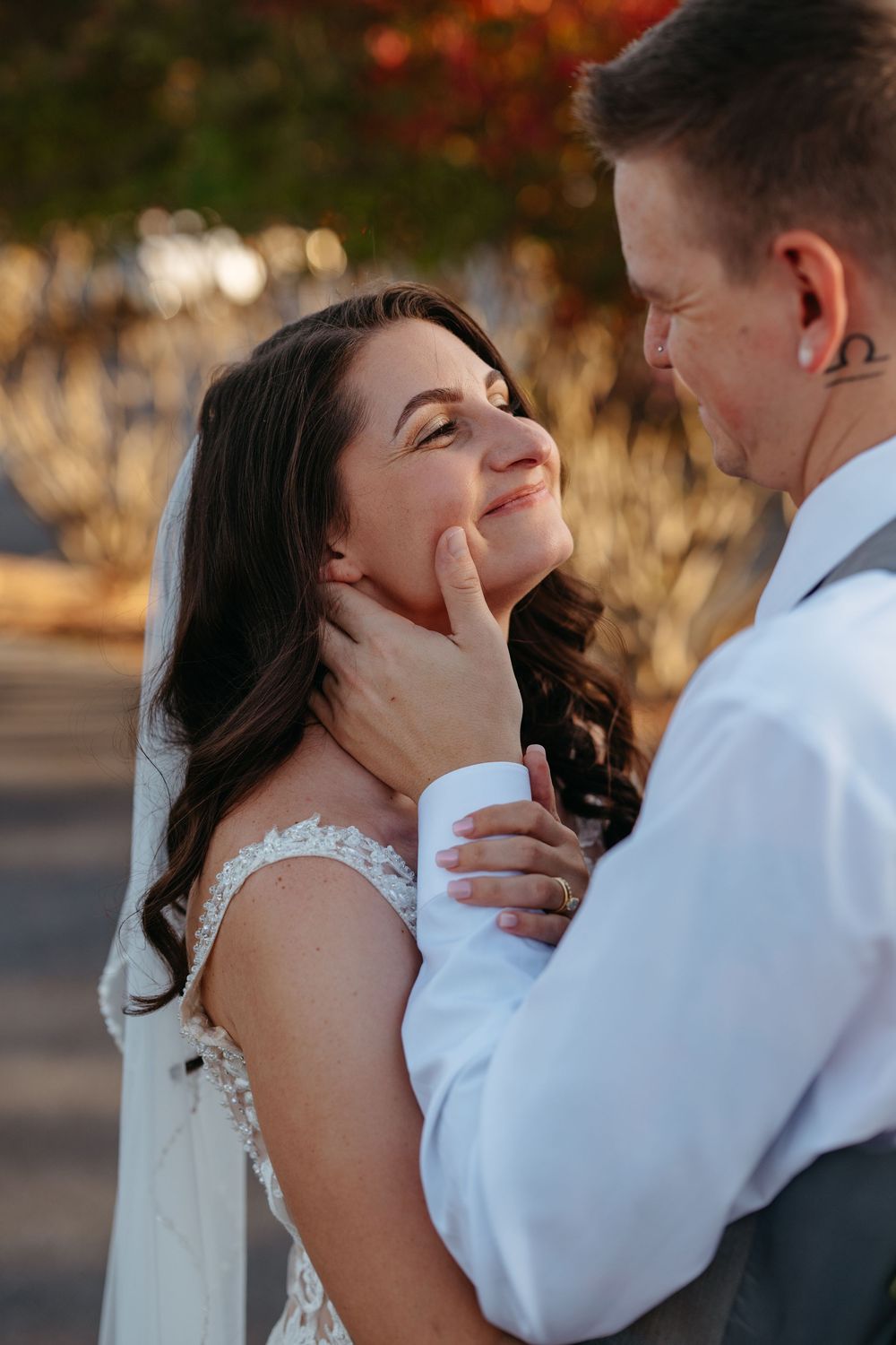 A joyful couple shares a tender moment during their wedding photoshoot outdoors.