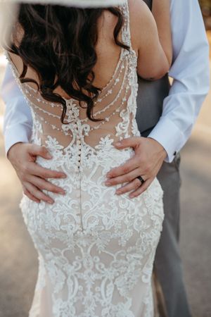 Close-up details of intricate white lace and beading on back of wedding gown.