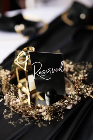 Black place cards with gold edges and delicate dried baby's breath flowers create an elegant wedding table setting.