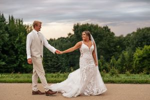 A couple shares romantic moments during their summer wedding celebration in a scenic outdoor setting at sunset.