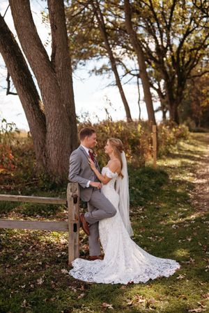 A tender moment between newlyweds photographed in a natural outdoor setting with fall foliage.