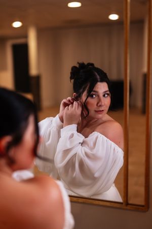 A person wearing a white top is photographed looking down while reflected in a mirror.