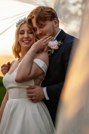 A tender moment between newlyweds during sunset, with soft golden light illuminating their intimate embrace.