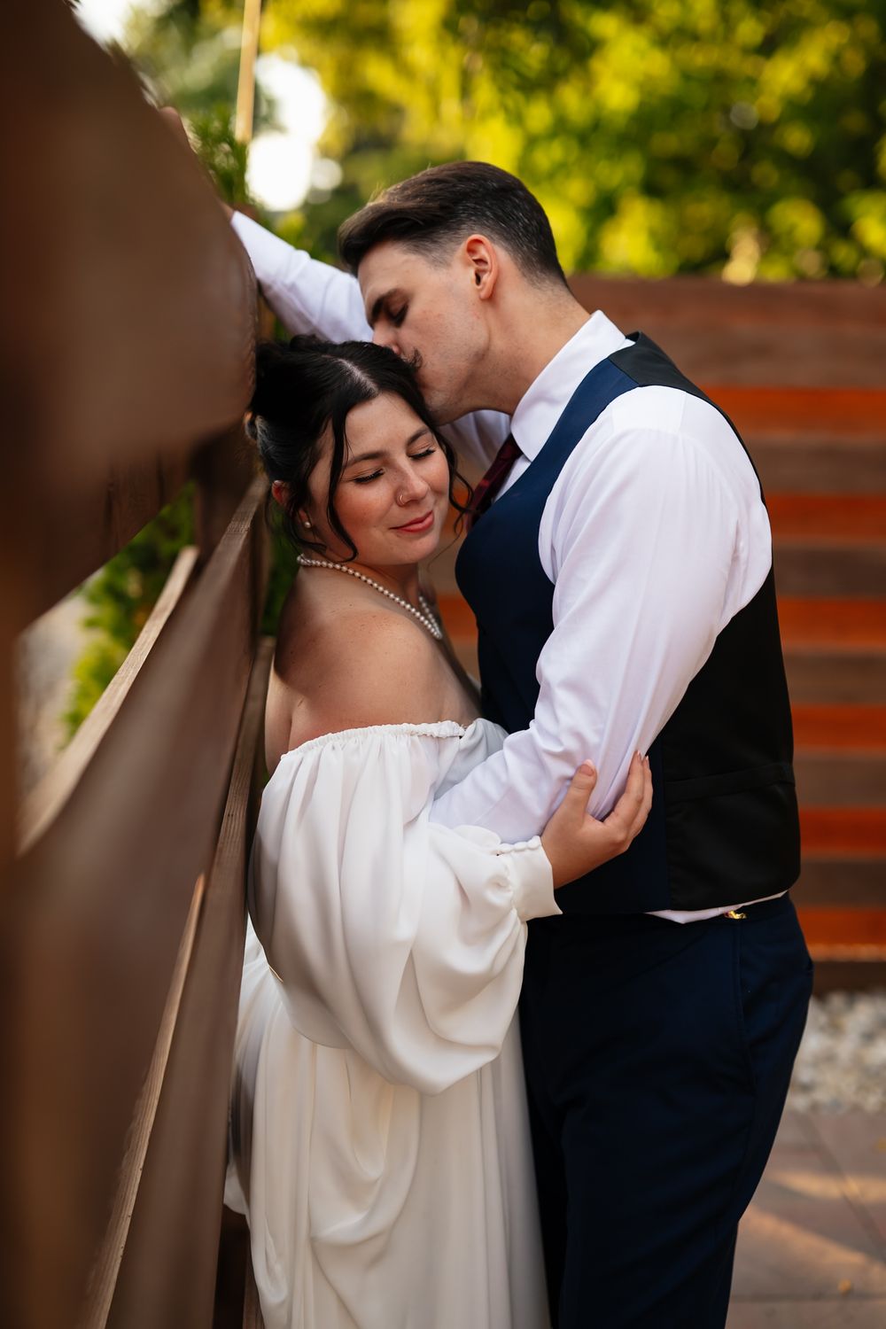 A romantic wedding couple shares an intimate embrace during their outdoor photo session in warm, natural lighting.