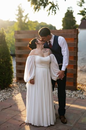 A romantic couple shares intimate moments in an outdoor setting at sunset as they pose for wedding photos on a patio.