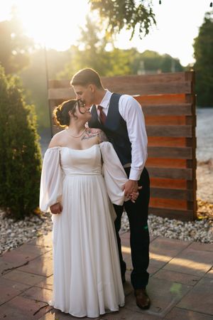 Sunset wedding portraits of couple against wooden wall with romantic golden hour lighting.