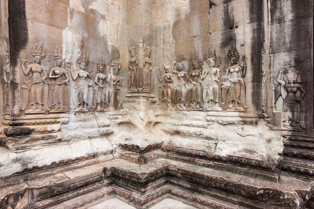 Ancient stone pillars and corridors of Angkor Wat temple ruins in Cambodia shown in a panoramic view.