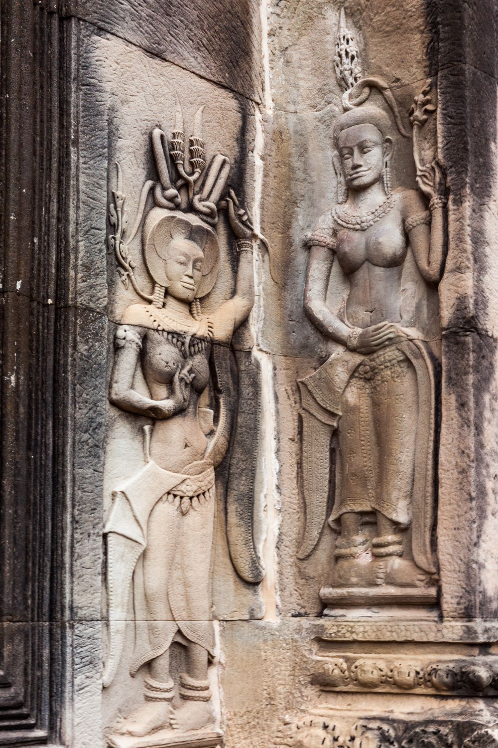 Ancient stone carvings of Apsara dancers in traditional dress adorn the walls of Angkor Wat temple in Cambodia.