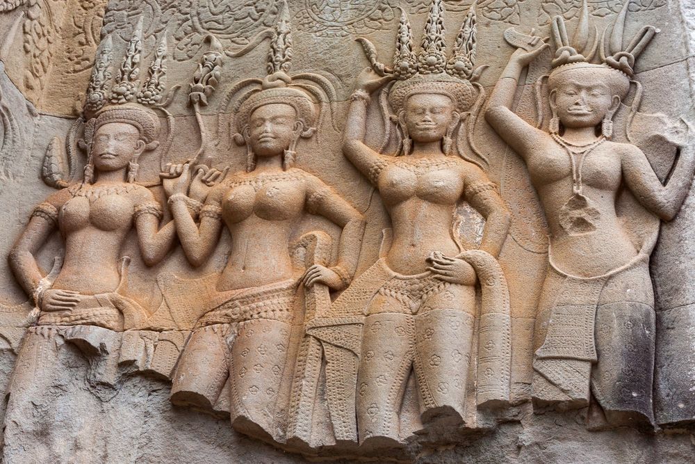 Ancient Khmer stone carvings depicting dancers and mythological figures adorn the walls of Angkor Wat temple in Cambodia.