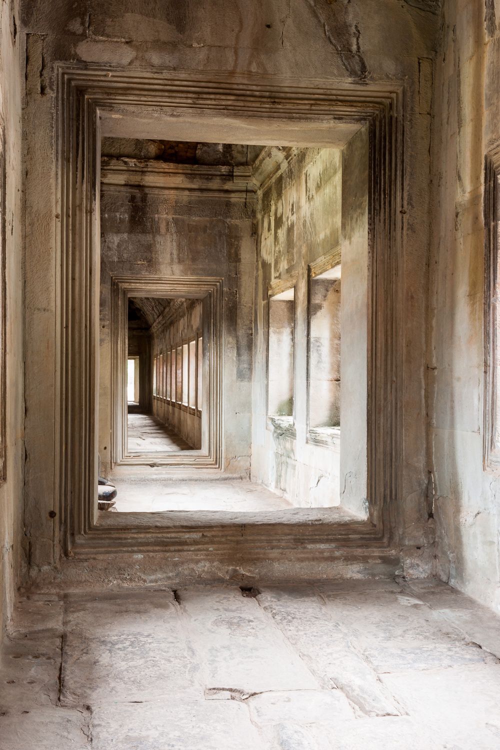 Long hallway in ancient stone temple with repeating columns and archways creates dramatic perspective at Angkor Wat, Cambodia.