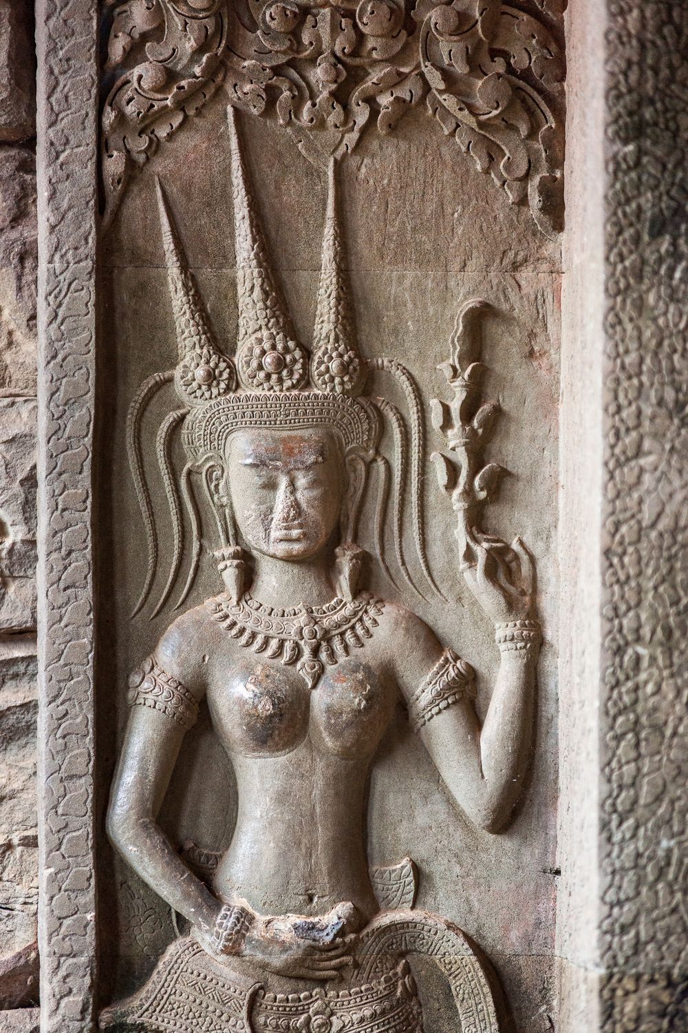 Ancient Angkor Wat temple wall carving showing intricate stone bas-relief of celestial figures in traditional Khmer style.