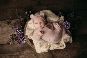A peaceful sleeping baby on a cozy tan blanket with delicate purple flowers in a rustic setting.