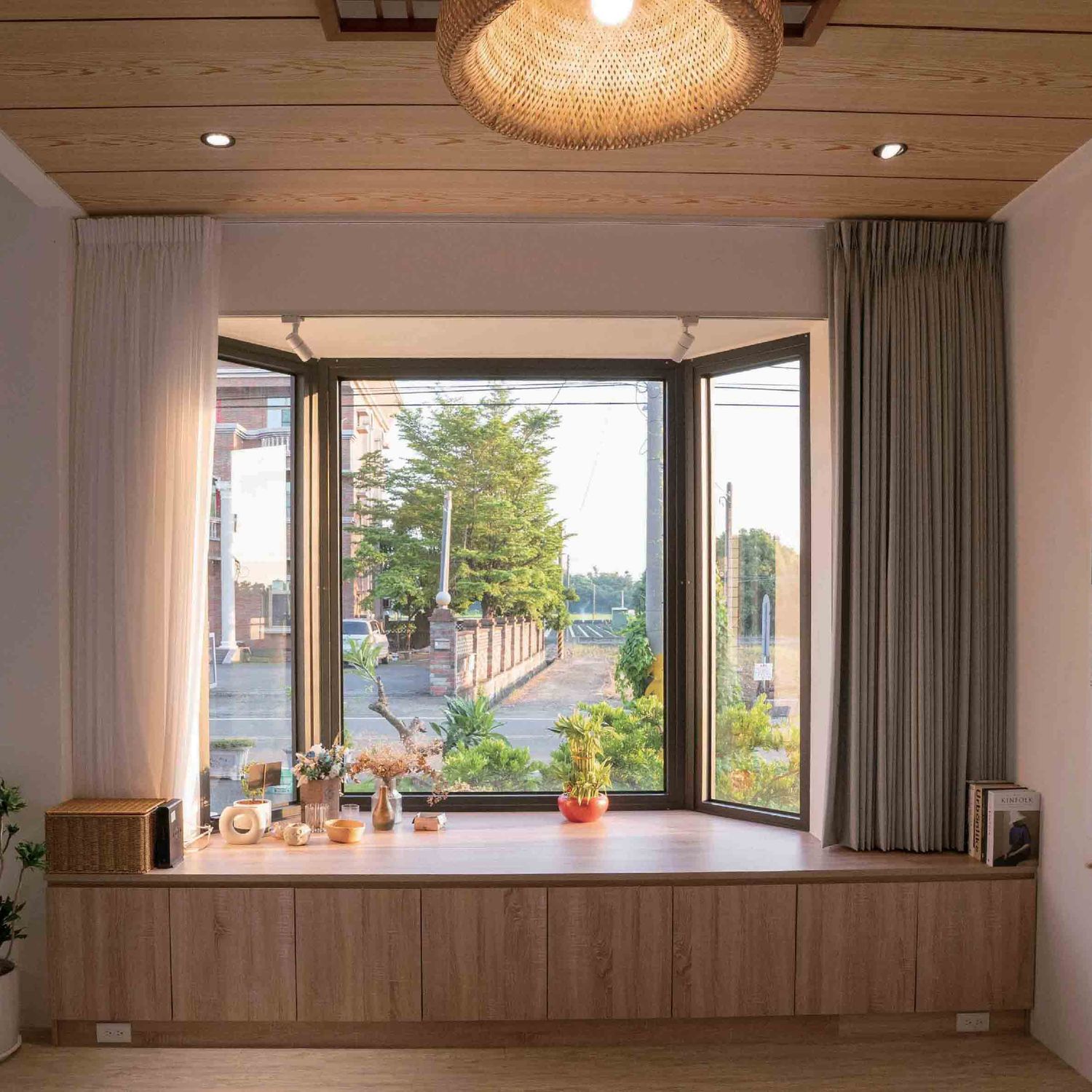Panoramic view of a modern minimalist room with large windows, woven pendant light, and wooden accent wall.