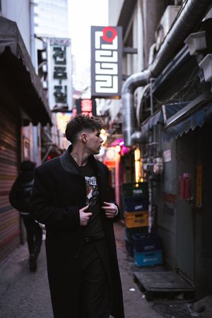 Dimly lit alleyway between buildings with neon signs in an Asian urban setting.