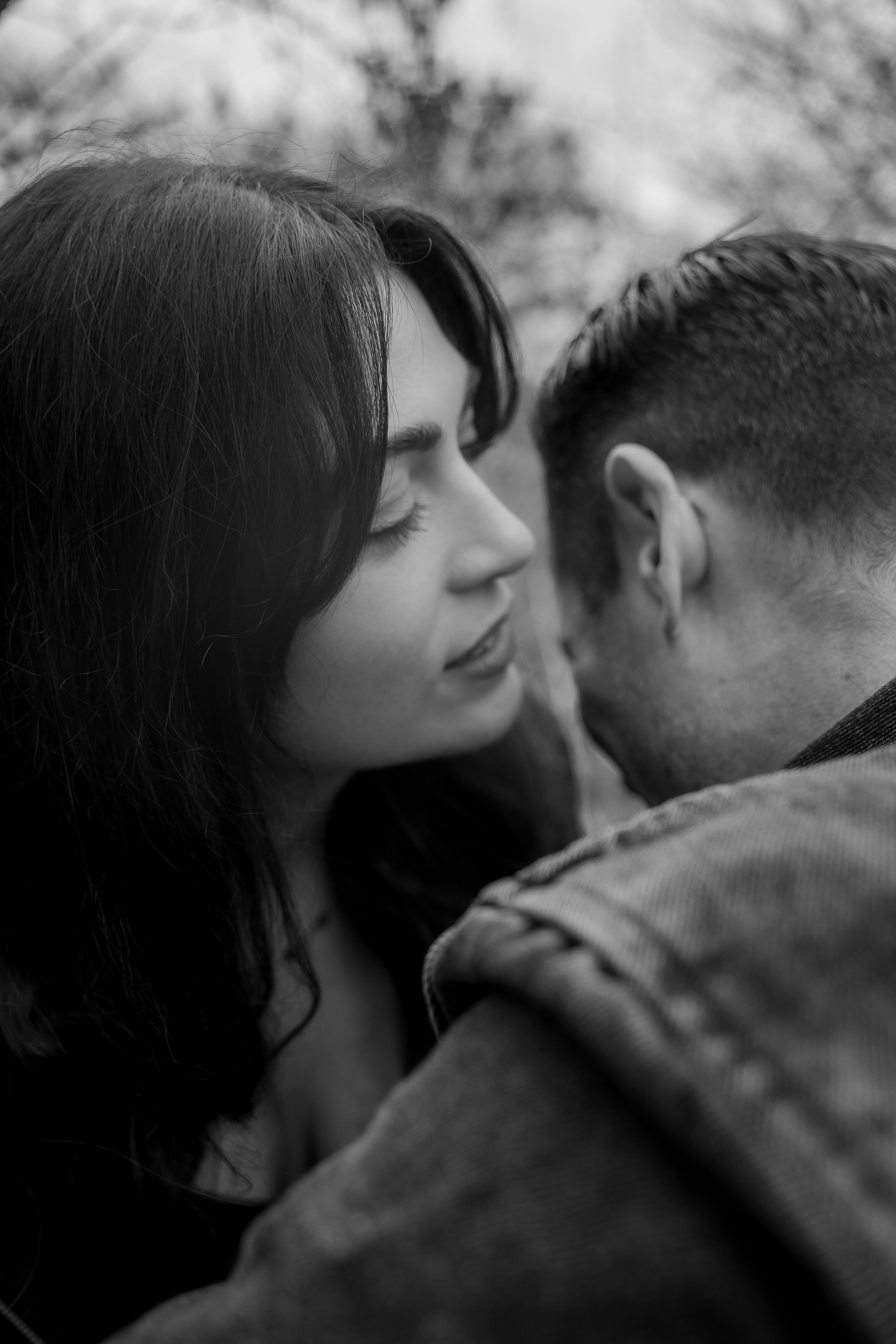 Black and white intimate portrait of a romantic couple sharing a tender moment outdoors.