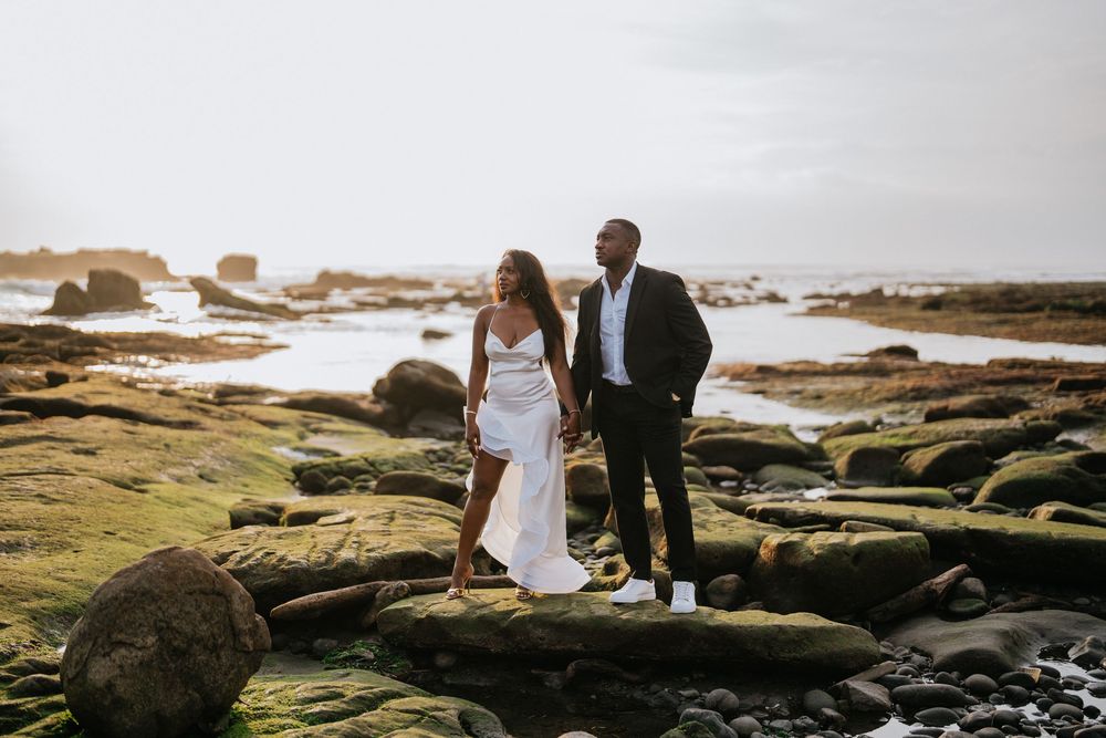 A romantic couple explores rocky tide pools along a scenic coastline at sunset.