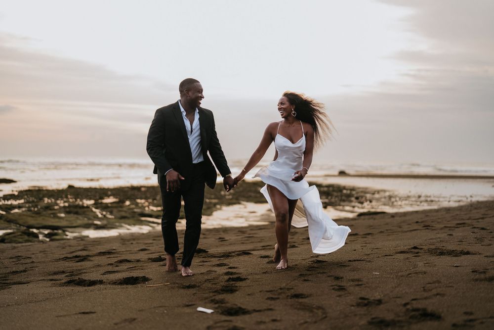 A couple walking and dancing together on a dark sandy beach.