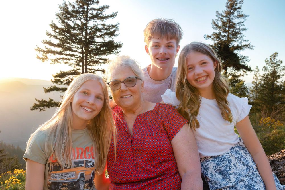Happy family gathering outdoors with evergreen forest and sunset creating warm atmosphere.