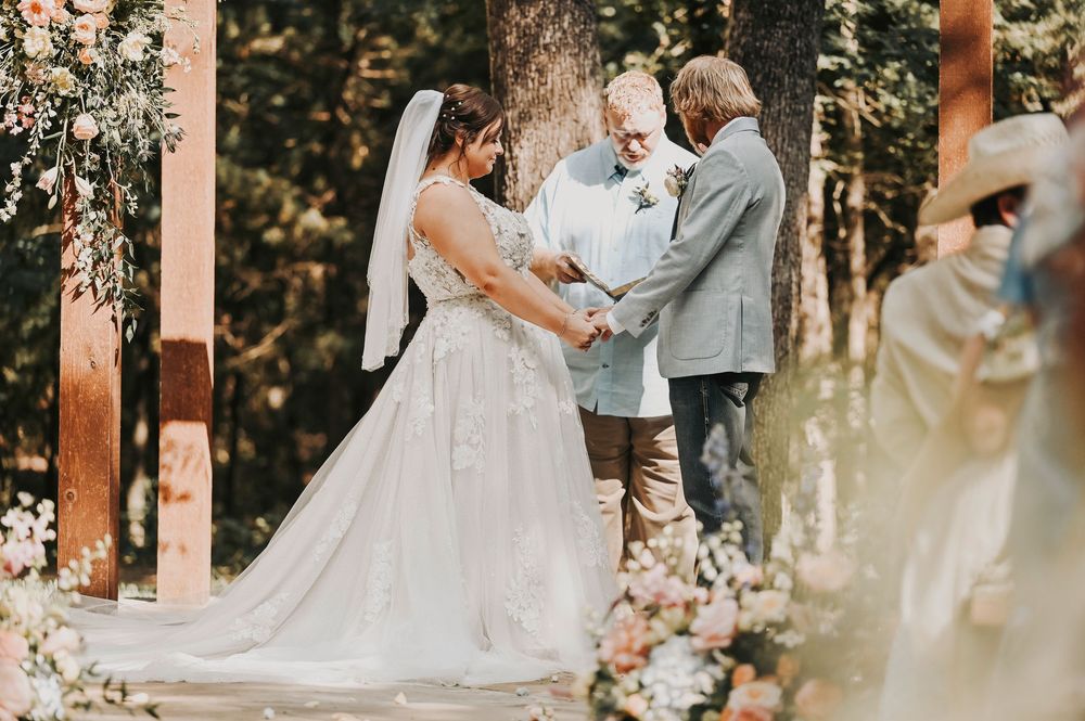 Couple exchanging vows under oak trees at Whispering Oaks