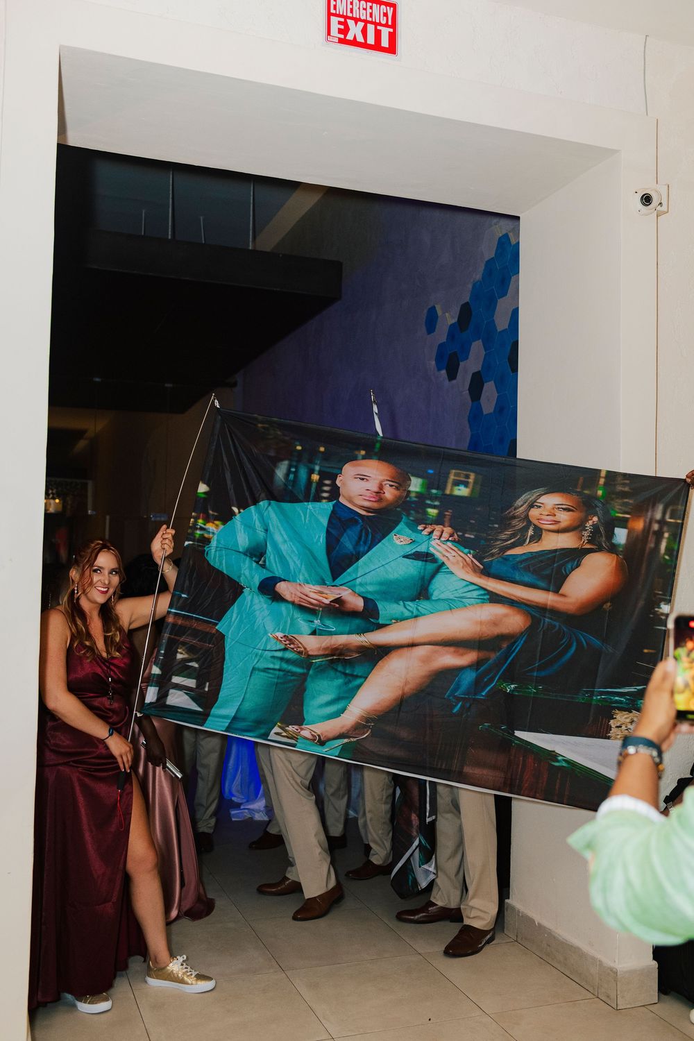 Wedding guests carry a large photo display through a doorway during the reception celebration.