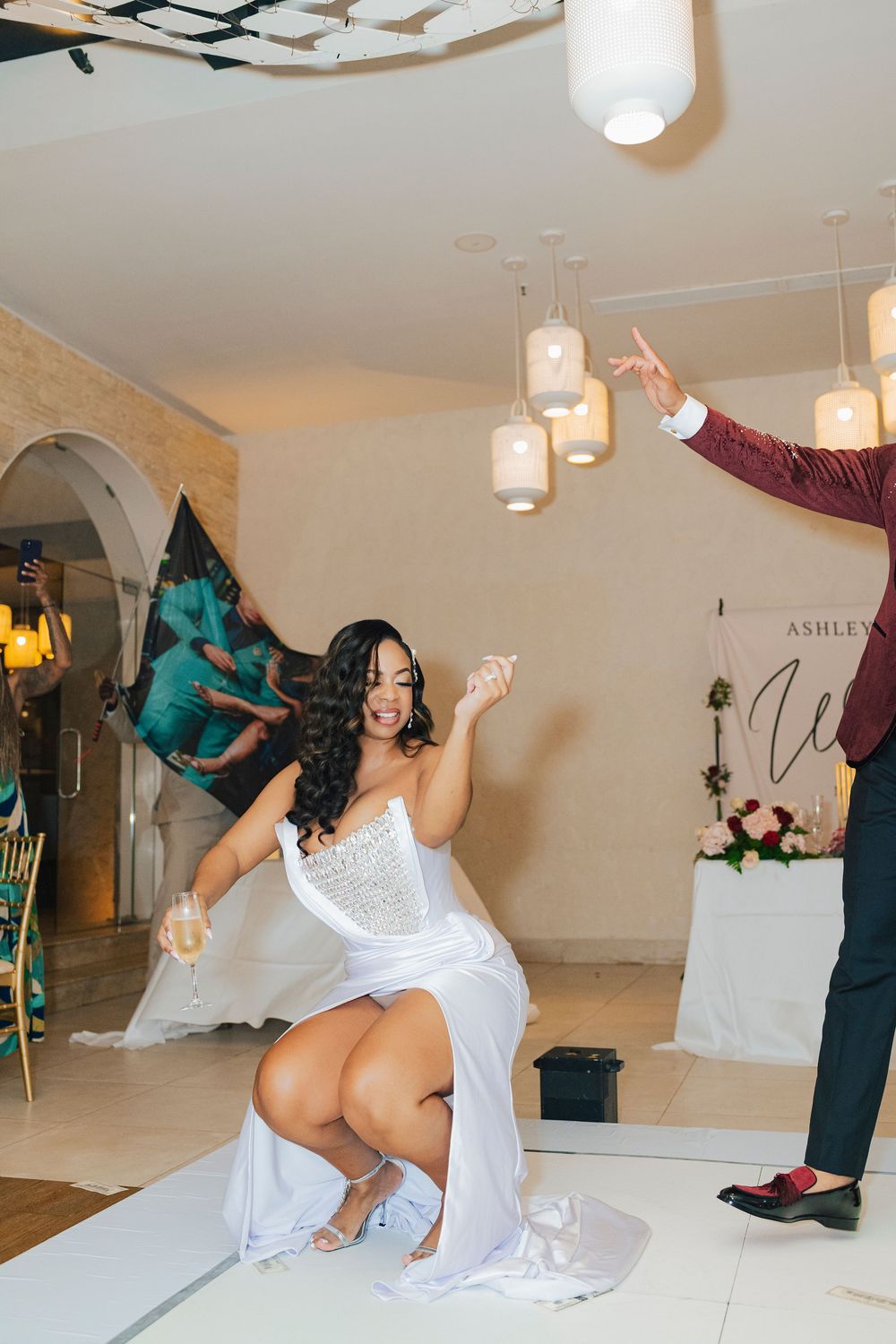 A couple performs an energetic dance routine at an elegant indoor venue with pendant lighting.