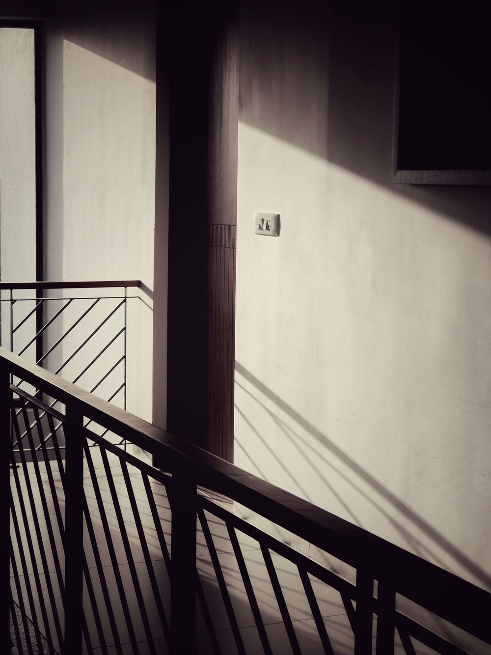 Minimalist architectural detail showing diagonal shadows cast by railings on white walls.