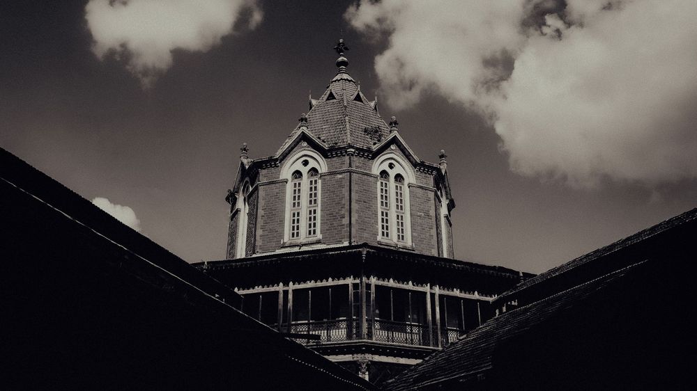 Dramatic cloudy sky framing Victorian architecture in a moody panoramic composition.