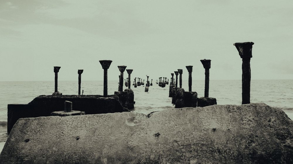 Row of silhouetted posts or pillars on a horizon line against a minimalist sky.