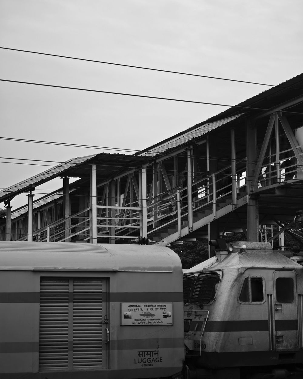 Black and white photo showing a series of train cars or railway carriages lined up at a station platform.