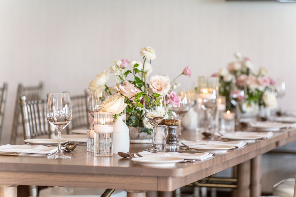 Long dining table decorated with pink and white floral arrangements for a wedding reception.