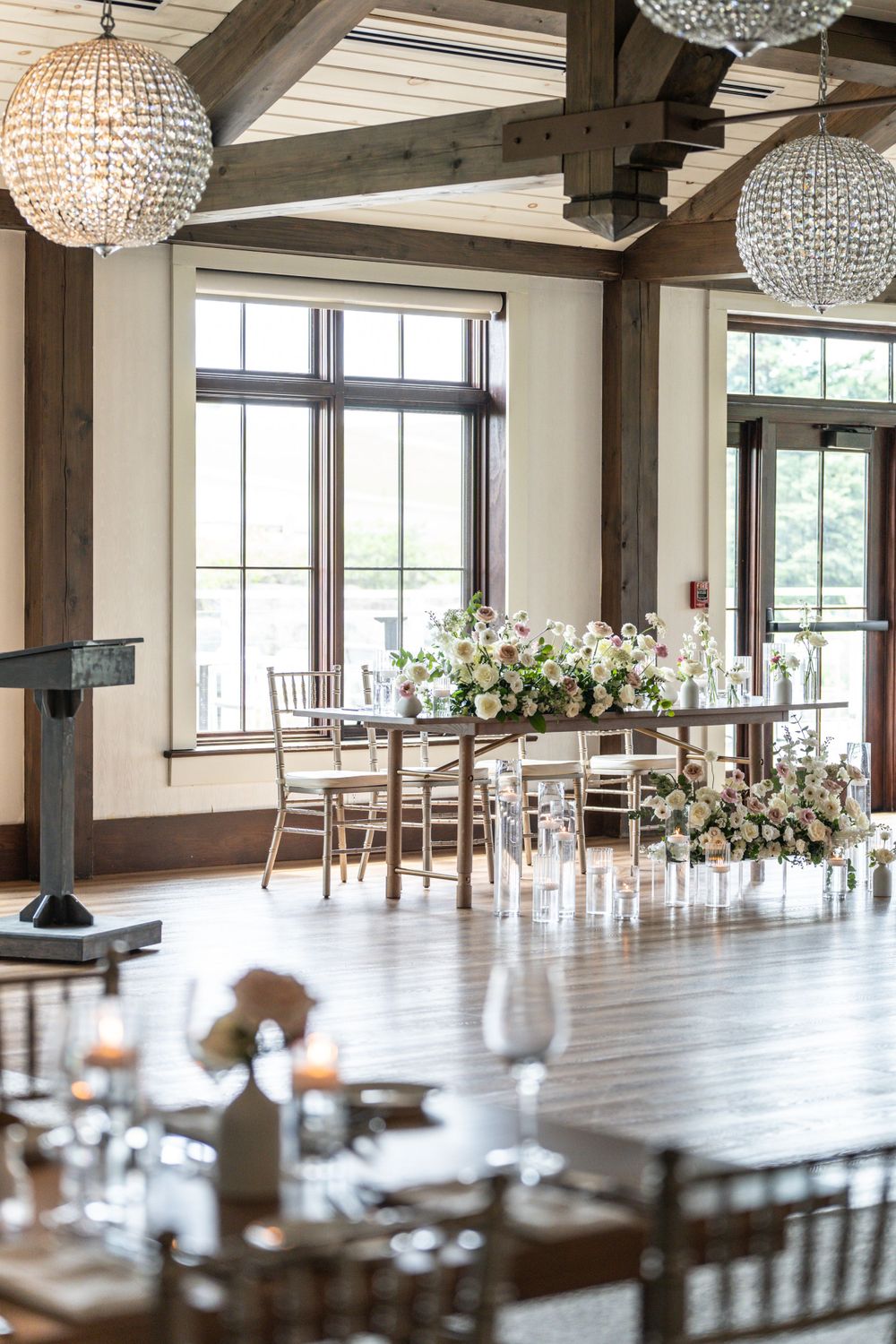 Rustic-elegant event space with crystal chandeliers and exposed wooden beams.