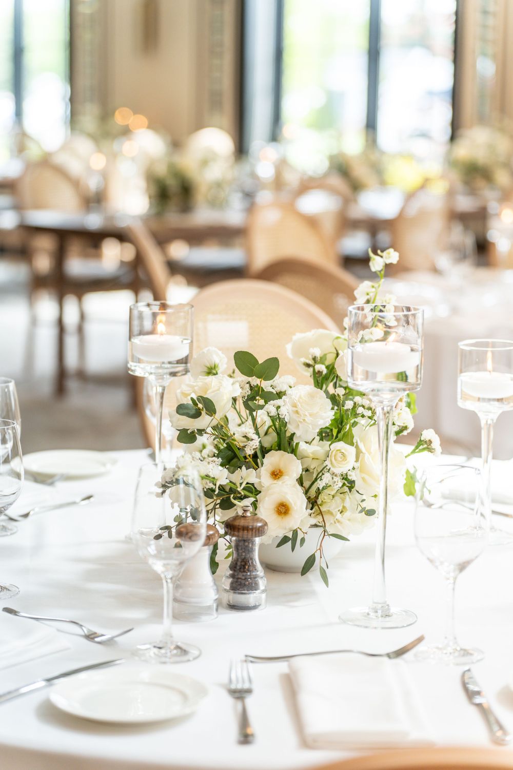 Wedding table settings with white floral centerpieces and crystal stemware.