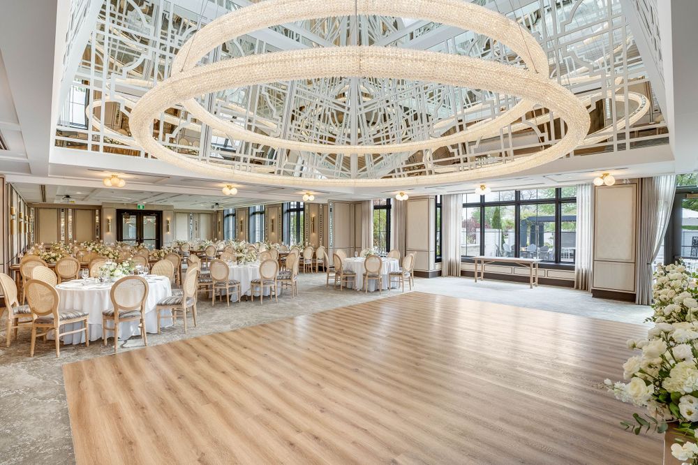Spacious white event venue with arched architectural details and modern lighting fixtures.