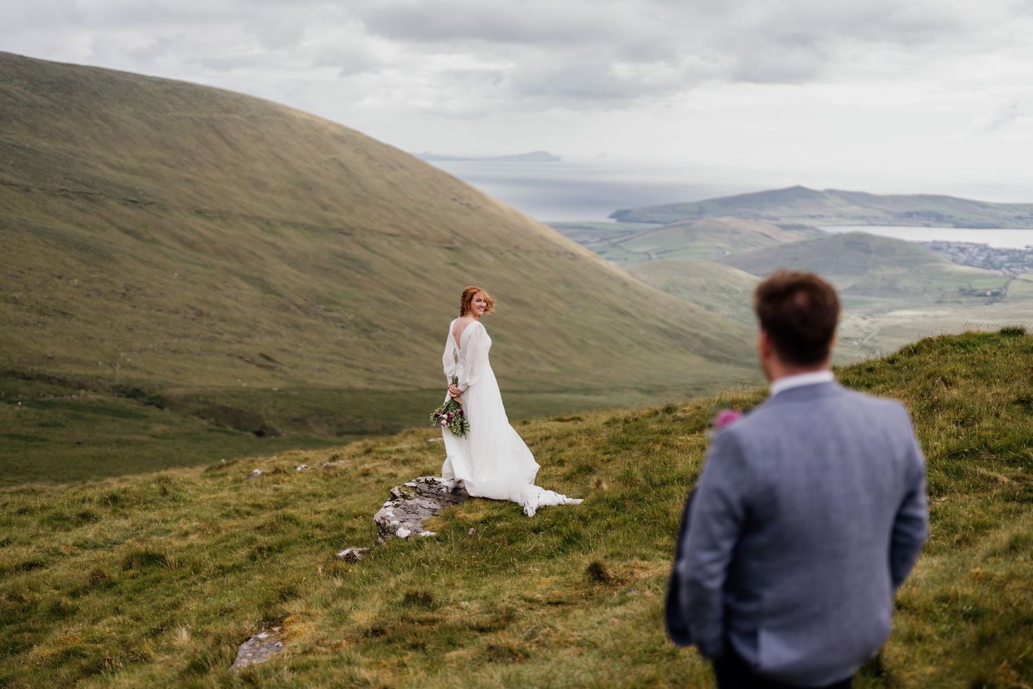 Wedding photography on hillside overlooking dramatic mountain landscape.