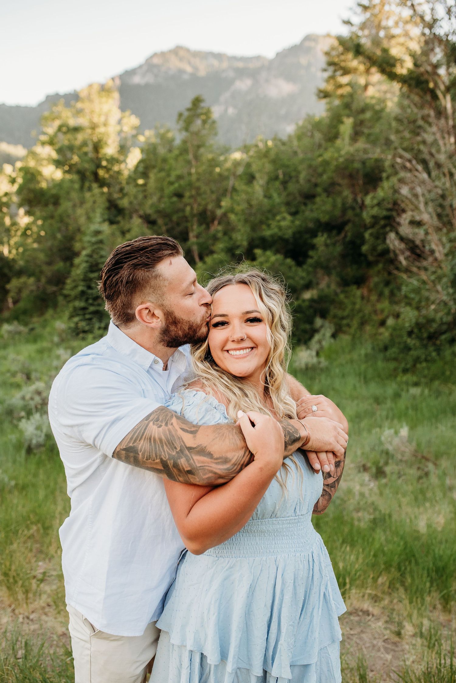 Romantic couple embracing in mountain meadow during golden hour.