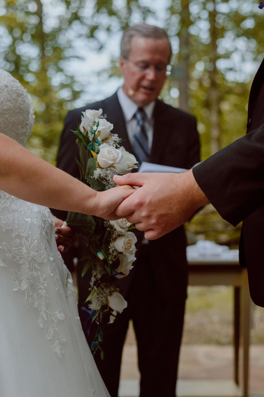 Close up of couple holding hands during wedding ceremony while exchanging vows.