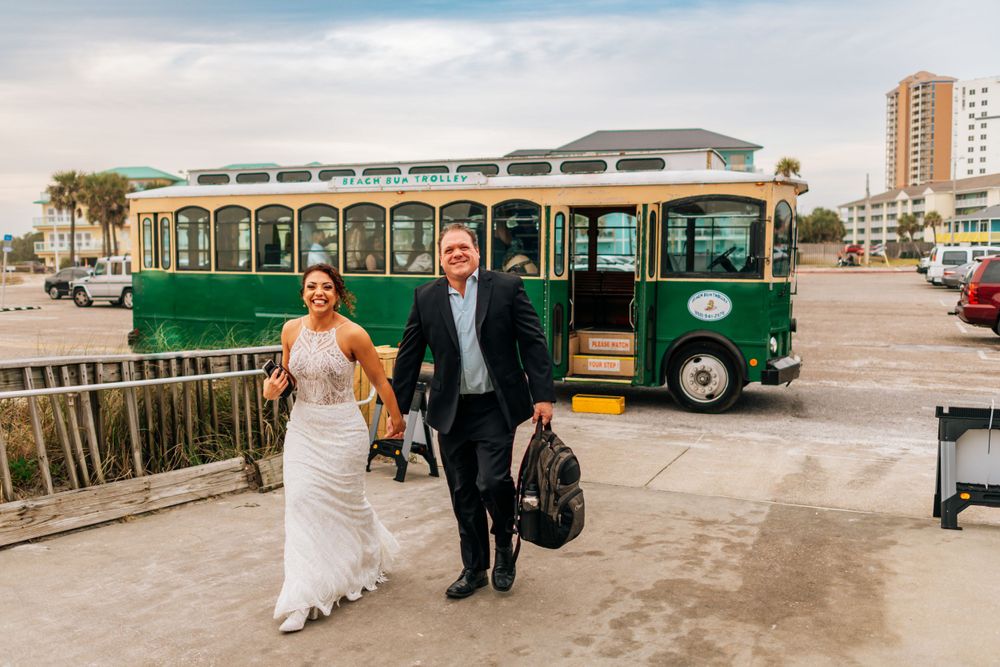 Newlyweds walking together with vintage green trolley in background.