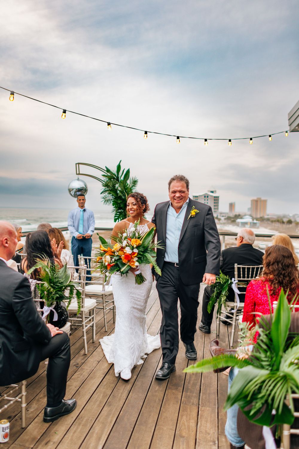 Wedding celebration on rooftop deck with string lights and tropical decor.
