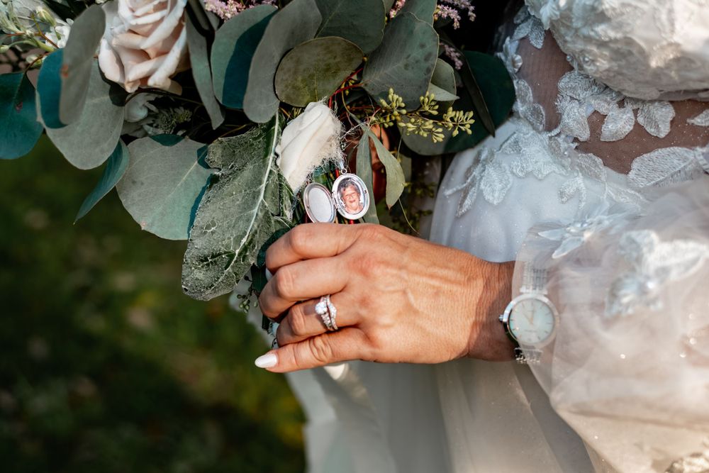 Close-up of wedding ring and watch with floral bouquet in background.