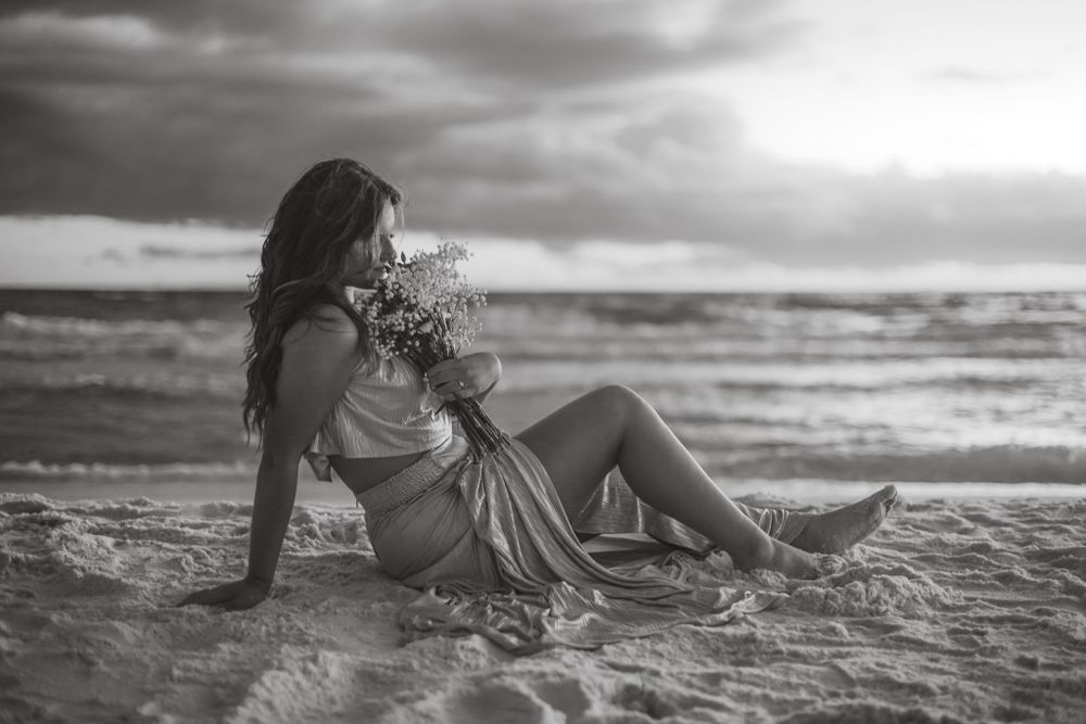 Senior portrait holding a bouquet of flowers on the Seaside beaches off 30A in Santa Rosa Beach Florida during sunset in Black & White style