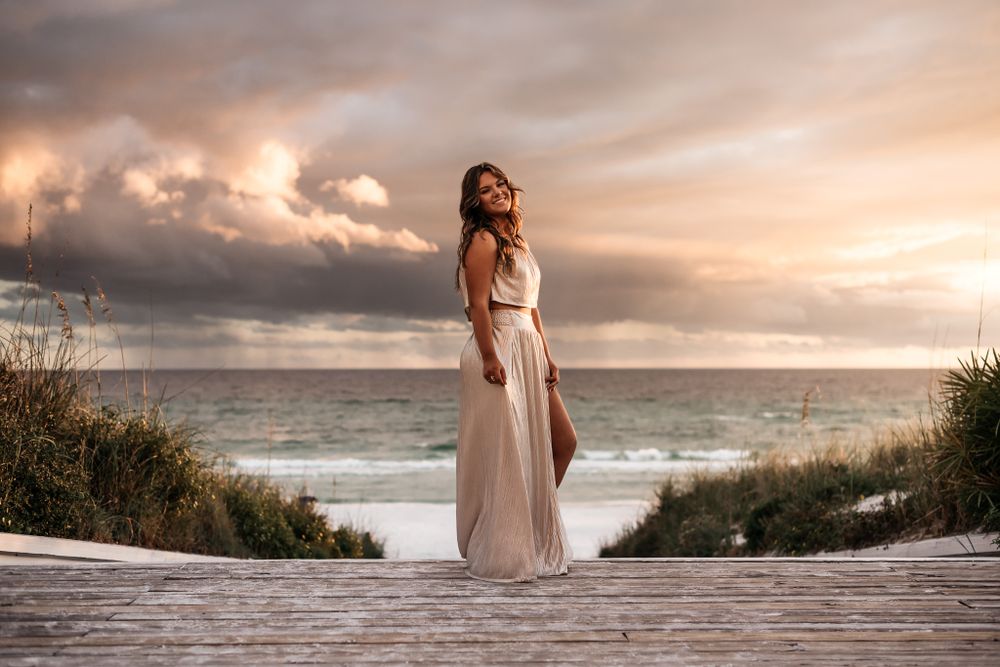 Breath taking portrait of a gorgeous Senior at the footsteps of Seaside Beach Access on 30A during a dramatic sunset photo session