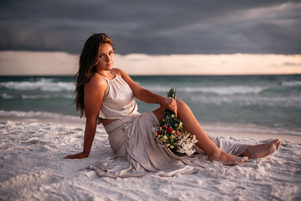 Beach portrait session with moody storm clouds at sunset.