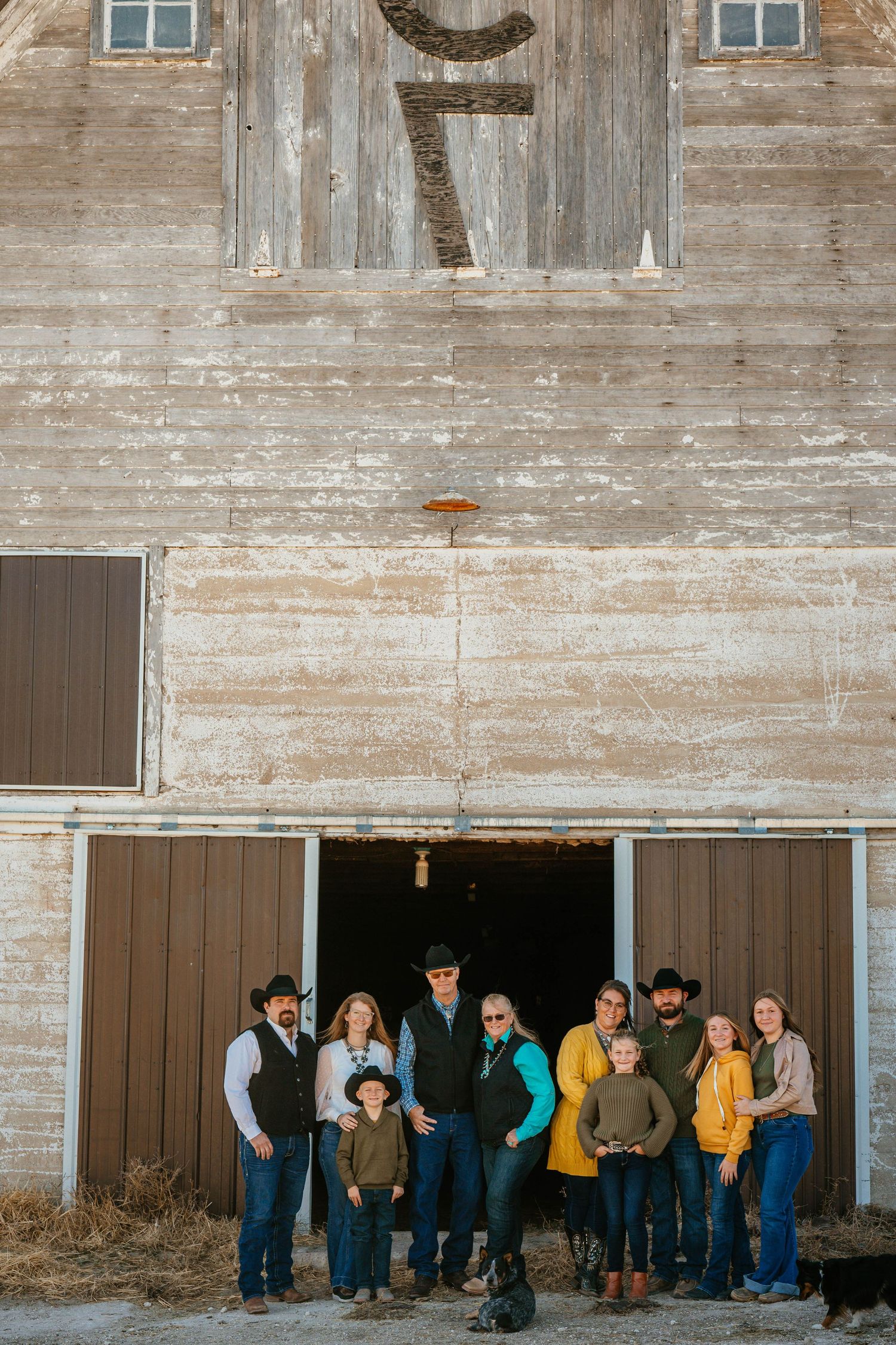 Western-styled family group poses together in tall golden grass during sunset.