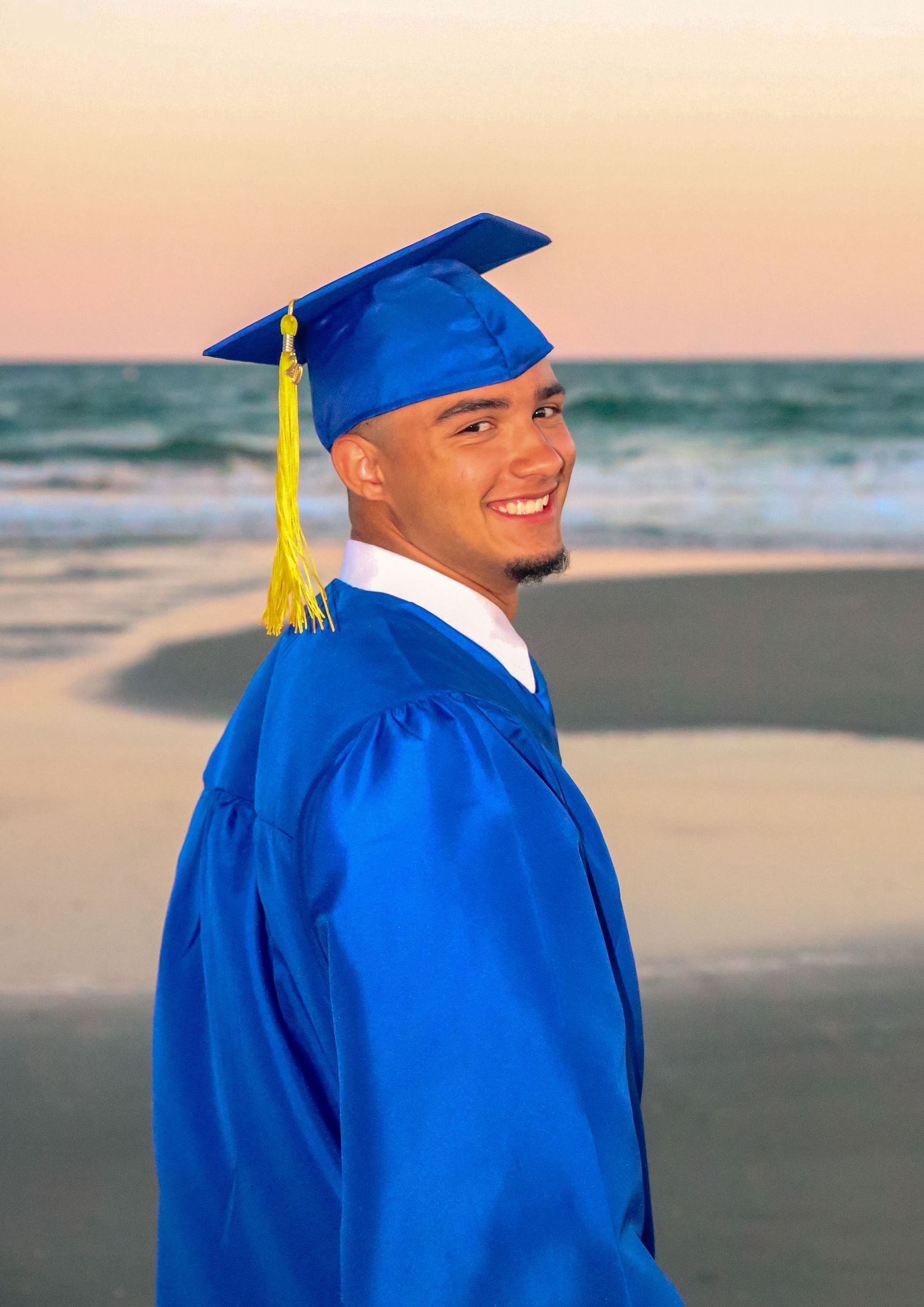 Senior posing in cap and gown in nature setting on the beach, Windsor Ontario taken by Tasha Cannaday.