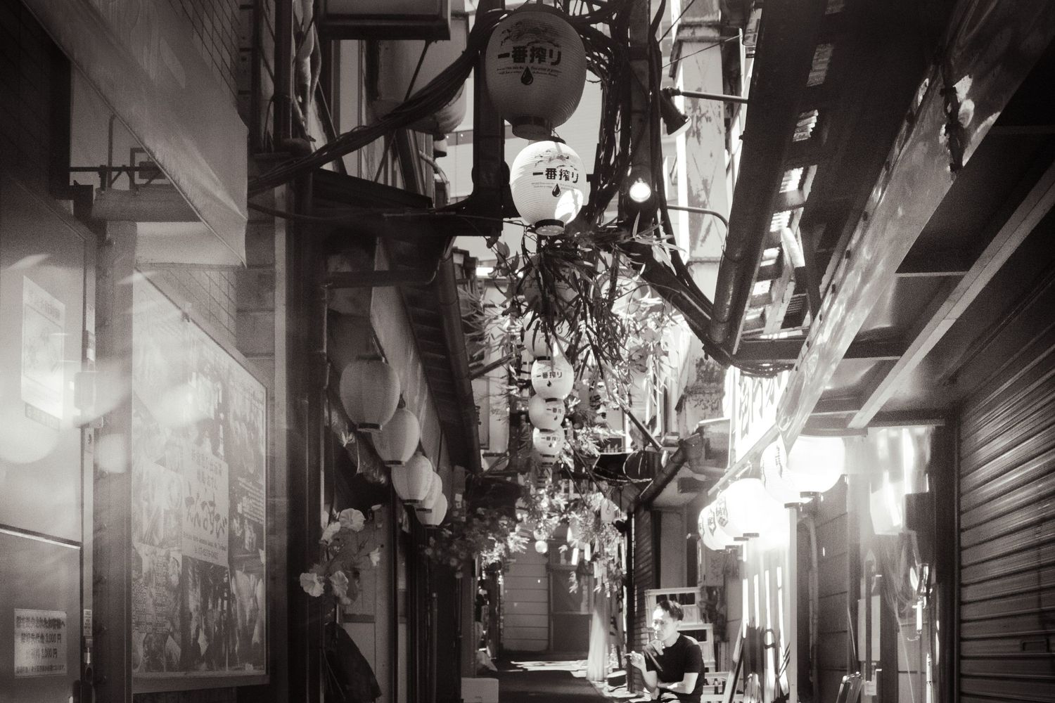 Moody black and white street scene with hanging lights and architectural details in an urban setting.