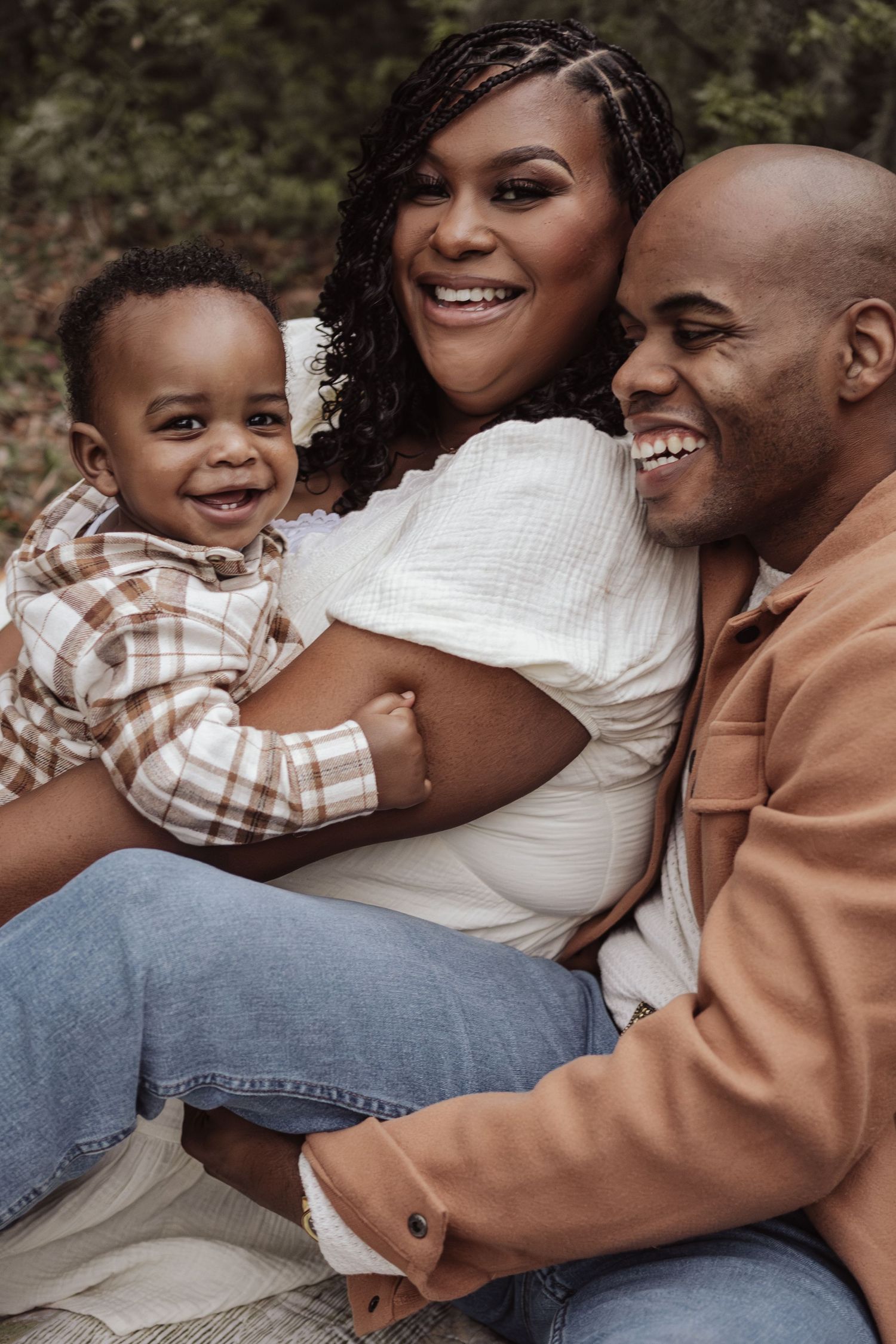 A joyful family shares laughter and embraces while sitting together outdoors in casual attire.