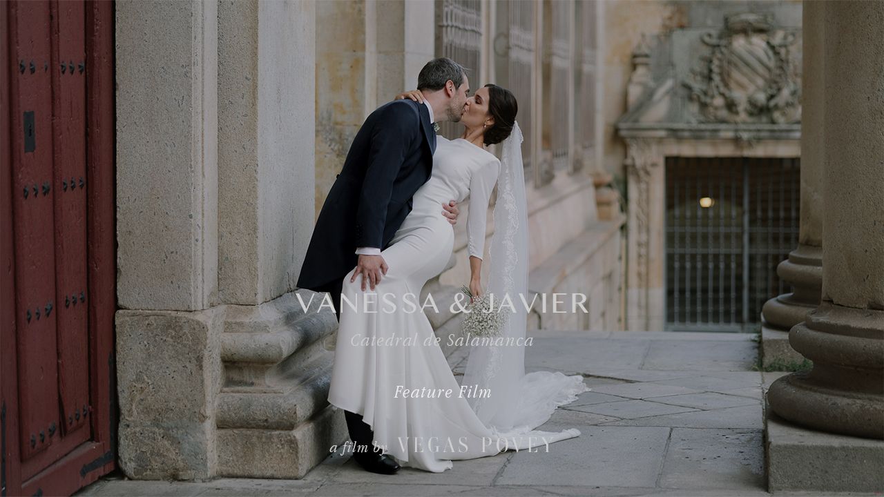 A romantic garden wedding scene with guests gathered in the background during a tender kiss moment.
