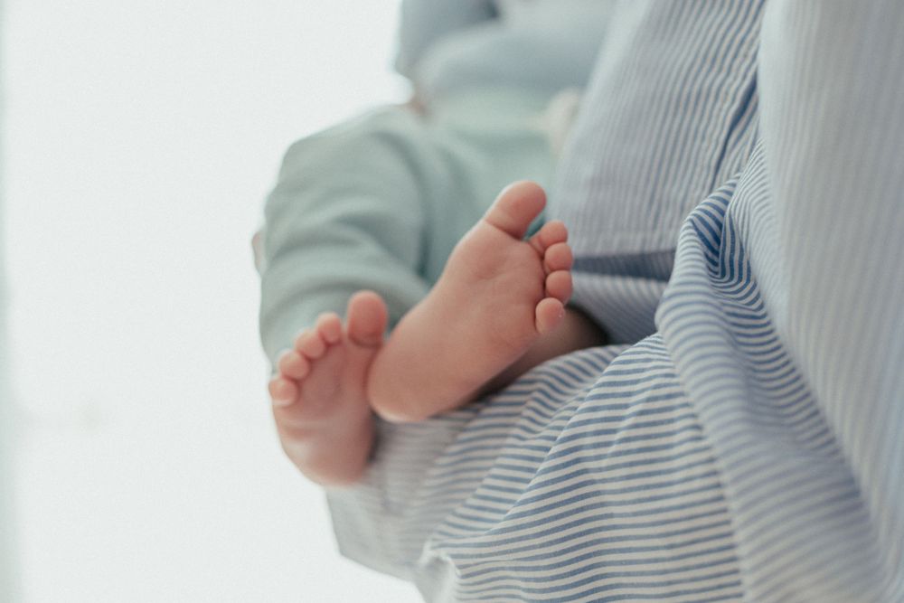 Close up of tiny baby feet wearing striped pajamas against a light background.
