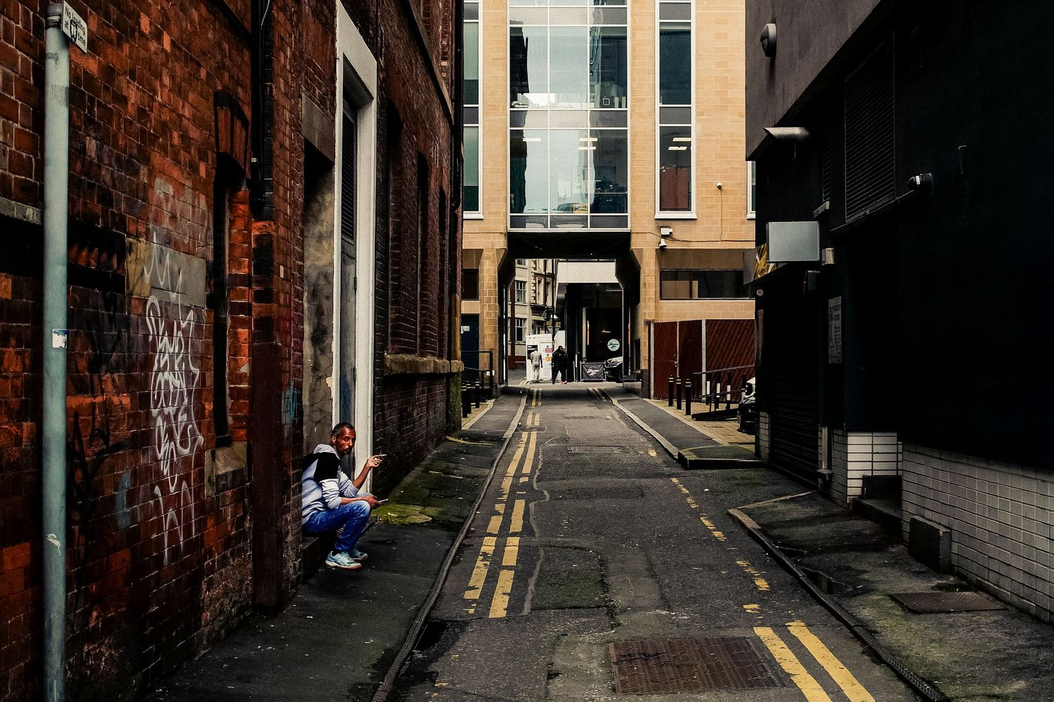 Narrow urban alley between brick buildings with yellow street markings.